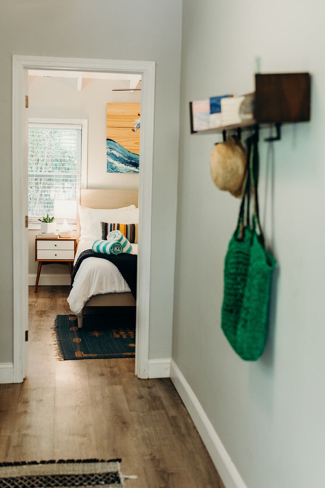 A bedroom with a bed, bedside table, and a window with blinds.