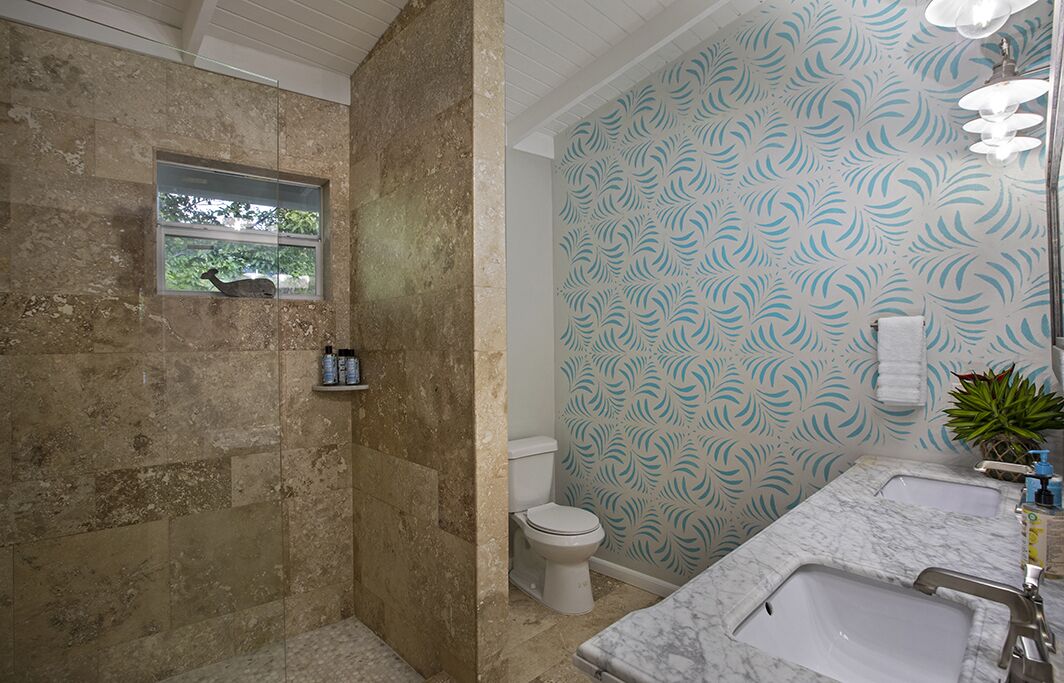 Un baño con lavamanos de mármol, inodoro y zona de ducha.