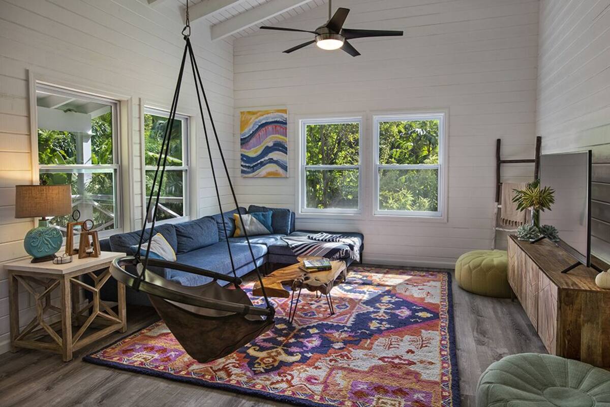 A cozy room with a hanging chair, a sofa, and a patterned rug.