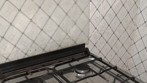Una cocina con estufa a gas, cuatro hornillas y campana extractora.