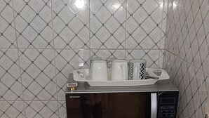 Una cocina con microondas en la encimera, un lavabo y un salpicadero de azulejos.