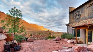 A rustic building with a large wheel on the facade, surrounded by a rocky landscape and sparse vegetation. - Hideout at the Rim - Moab's Best Kept Secret (Moab)
