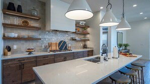 A modern kitchen with a large island, pendant lights, and built-in shelves. - Arcadia 71 | Private Hot Tub * Fire Pit * Pool Table * Kid's Nook * Views (Santa Clara)