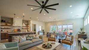 A spacious living area with a sofa, armchairs, a coffee table, and a dining area with a table and chairs. - Arcadia 71 | Private Hot Tub * Fire Pit * Pool Table * Kid's Nook * Views (Santa Clara)