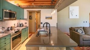 A modern kitchen with a central island, green cabinets, and a large window. - Perfect Family Vacation Getaway! (Pagosa Springs)