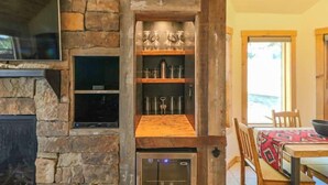 A stone fireplace with a built-in oven, shelves with glassware, and a dining area with a table and chairs. - Perfect Family Vacation Getaway! (Pagosa Springs)