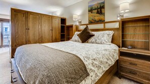 A bedroom with a large bed, wooden wardrobe, and a painting on the wall. - Lift House Lodge, Pet Friendly, Premium Studio Condo (Vail)
