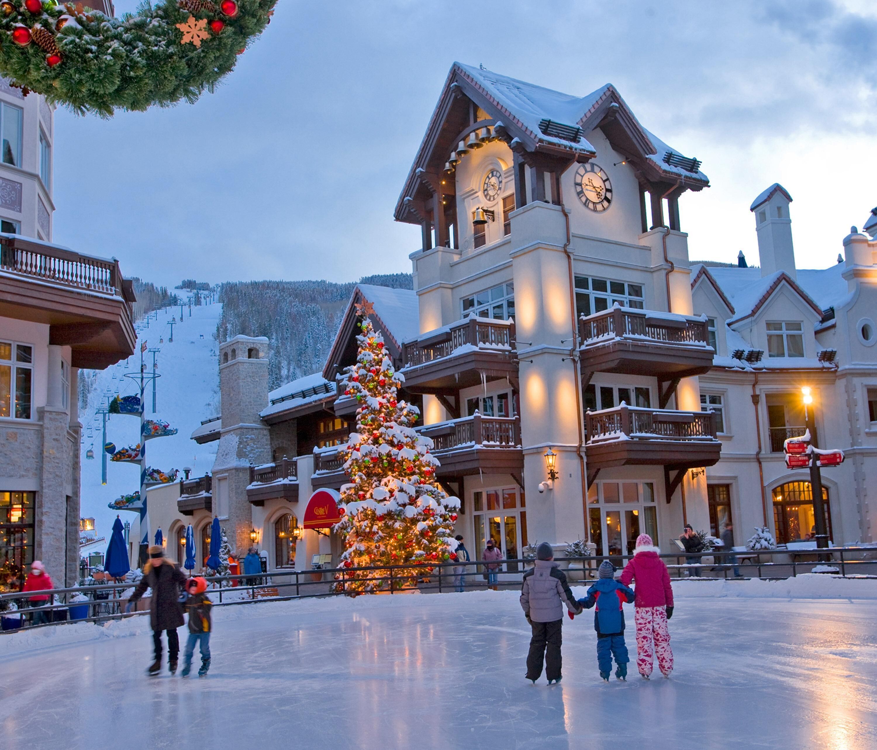 A hotel with a large Christmas tree, multiple balconies, and a ski lift in the background.
