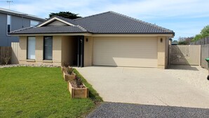 A single-story house with a garage, a front door, and a small porch. - Anglers Rest at Sunderland Bay (Sunderland Bay)