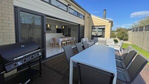 An outdoor patio with a grill, dining table, and chairs. - Anglers Rest at Sunderland Bay (Sunderland Bay)