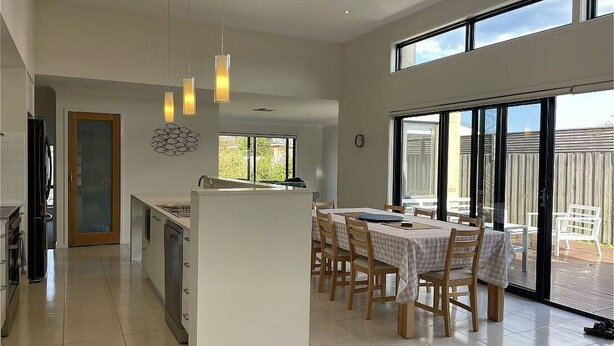 A spacious kitchen with a dining area, large windows, and a view of the outdoors. - Anglers Rest at Sunderland Bay (Sunderland Bay)