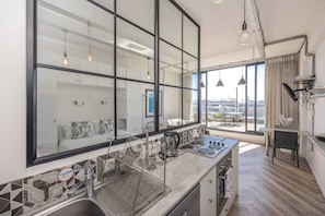 A modern kitchen with a large window, a dish drying rack, and a view of the city.