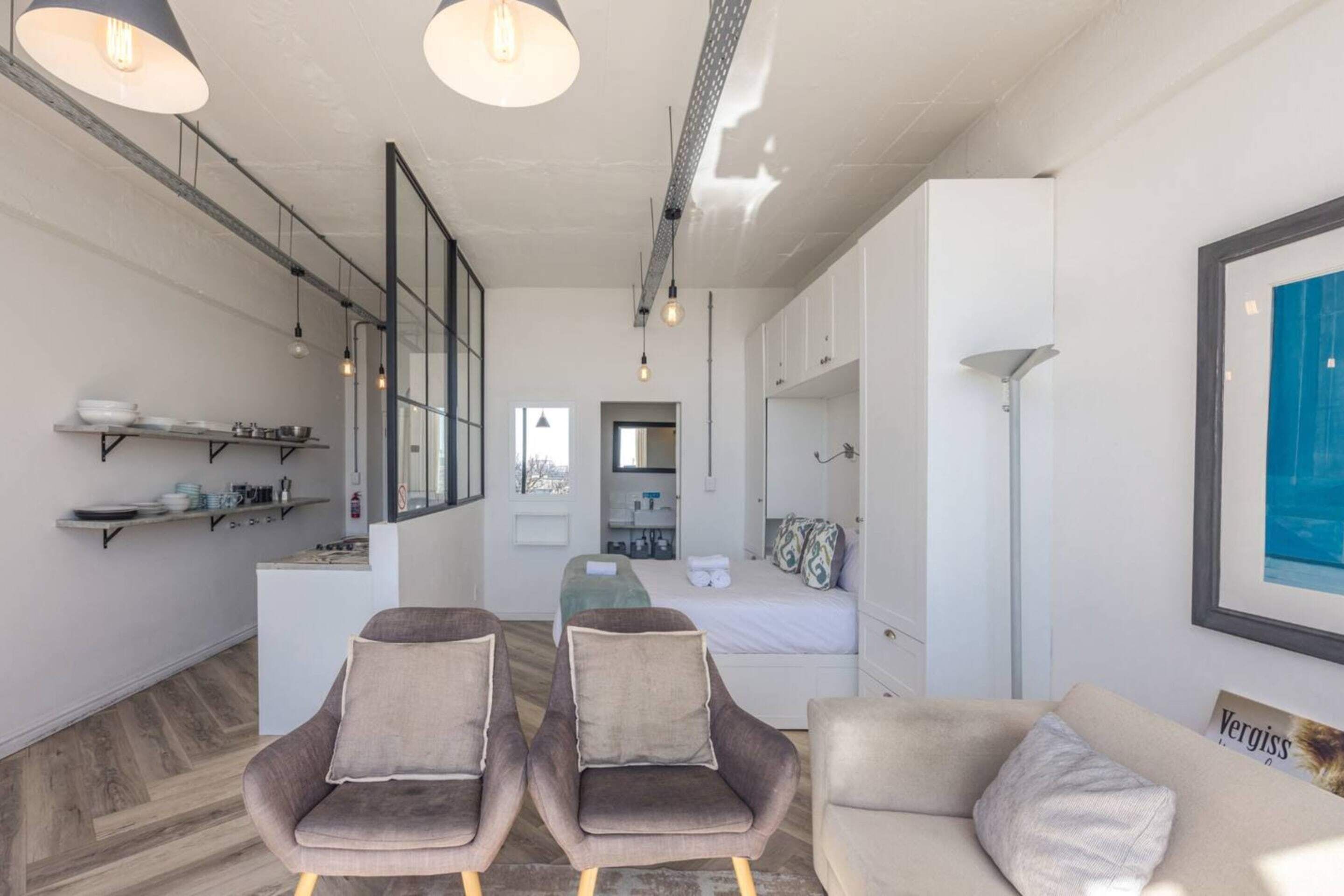 A modern, open-plan living area with a sofa, two armchairs, and a dining table.