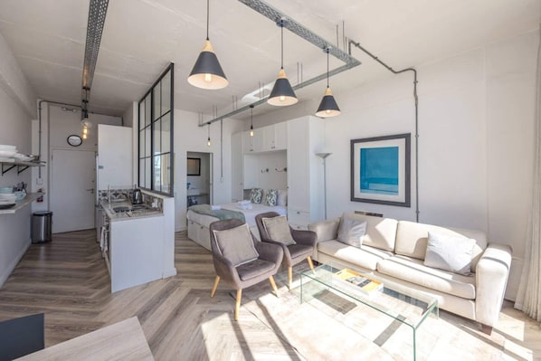 A modern living space with a kitchen, dining area, and a sofa set.