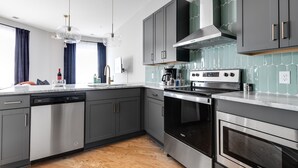 Una cocina moderna con gabinetes grises, electrodomésticos de acero inoxidable y salpicadero de azulejos.