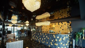 A modern hotel lobby with a central reception desk, large chandeliers, and a decorative honeycomb wall pattern. - Apartamente Stefan Resort 2 (Navodari)