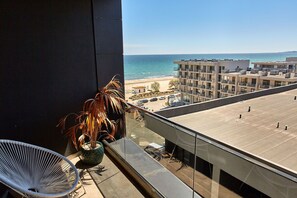 Un balcone con vista sulla spiaggia, un'area parcheggio e un edificio a più piani.