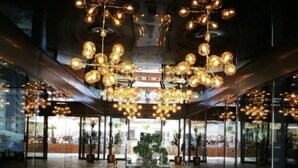 A lobby with a marble floor, a large decorative vase, and multiple hanging spherical light fixtures. - Apartamente Stefan Resort 2 (Navodari)