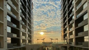 A modern hotel with a central pool surrounded by lounge chairs, reflecting the sky and clouds above. - Apartamente Stefan Resort 2 (Navodari)