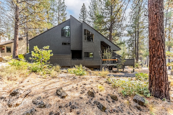 A modern house with a sloped roof, large windows, and a stone foundation.