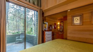 A bedroom with a large bed, a sliding glass door leading to a balcony, a dresser, and framed pictures on the wall. - LEIS06 - Great for Families, Hot Tub, Ping Pong, Bunk Rooms (Sunriver)