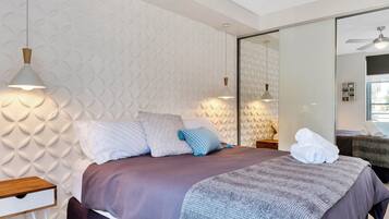 Een moderne slaapkamer met een bed, kussens, een nachtkastje en een bijzettafeltje.