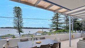 Un área de comedor al aire libre techada, con vista al agua y a los árboles.