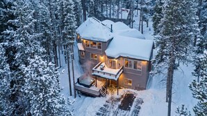 Ein zweistöckiges Haus mit Balkon, umgeben von schneebedeckten Bäumen.
