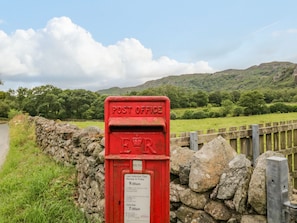 Una oficina de correos roja con un muro de piedra y una valla de madera al fondo.