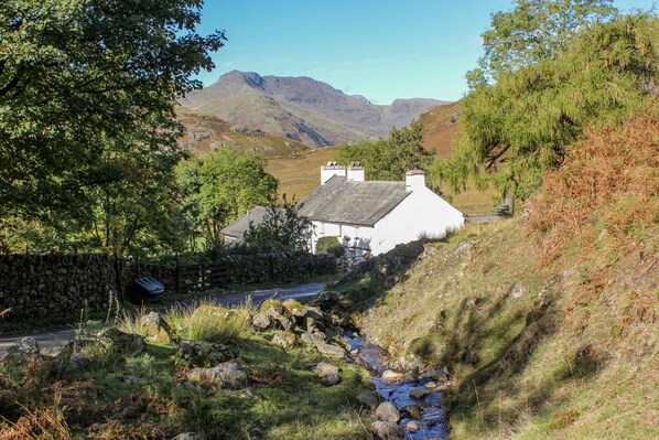 A white building with a stone wall and a stream in front. - Newfield Apartment 1 (Broughton in Furness)