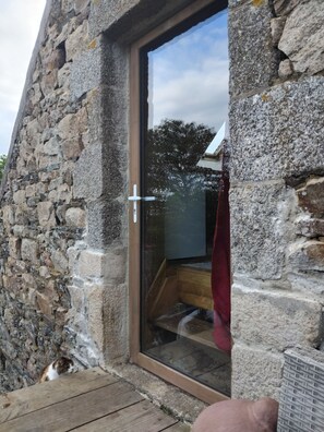 Un bâtiment en pierre avec une porte en verre, un plancher en bois et un chat visible.