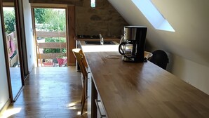 A spacious kitchen with a wooden countertop, a coffee maker, and a view of the outdoors. - Charmant Gîte 6 à 10 Personnes en Bord de mer (Lannion)