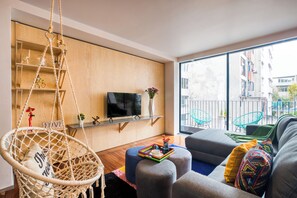 A modern living room with a hanging chair, a sofa, and a television. - ULIV Parque México (Mexico City)