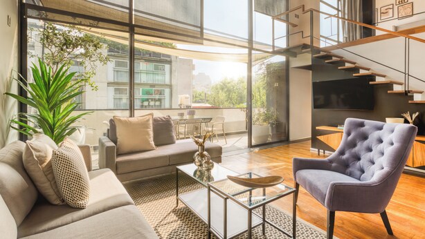 A modern living room with a sofa, armchair, coffee table, and large windows. - ULIV Parque México (Mexico City)