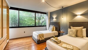 A modern hotel room with two beds, a large window, and a view of trees. - ULIV Parque México (Mexico City)