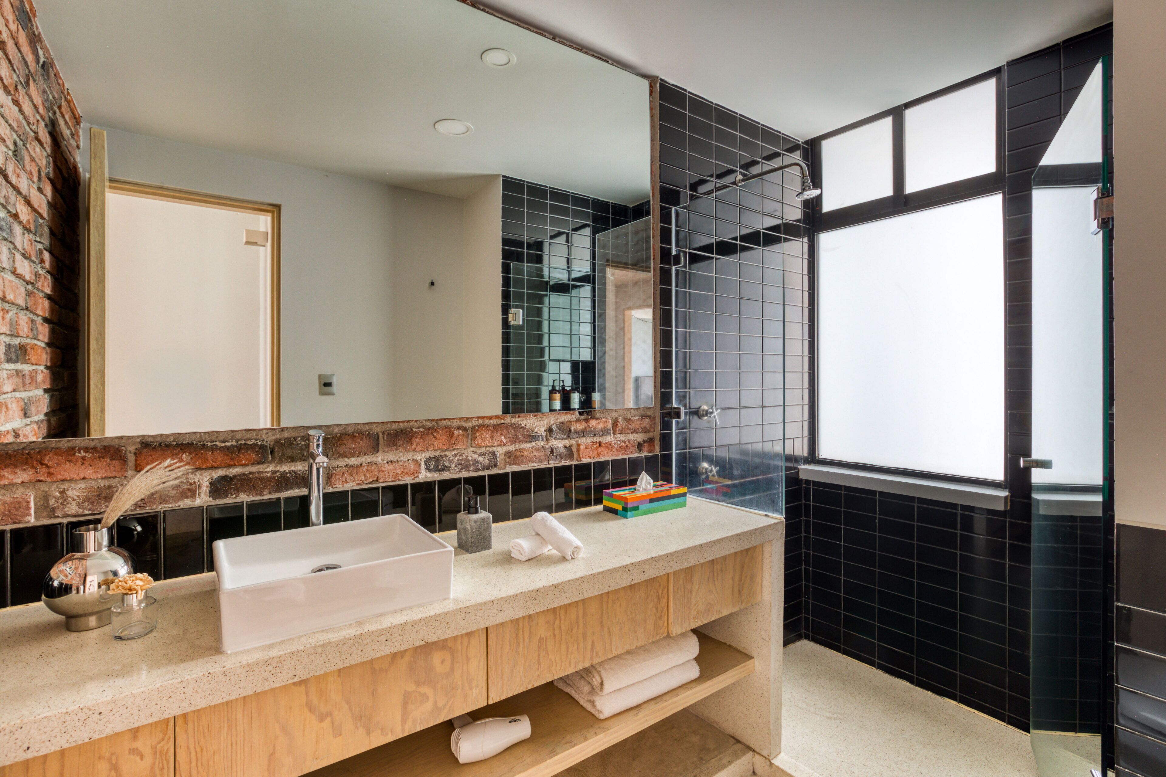 Un baño moderno con un espejo grande, un lavabo y una ventana.