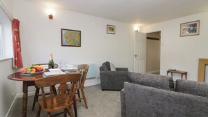 Un comedor con una mesa de madera preparada para dos personas, un sofá gris y una pequeña mesita auxiliar.