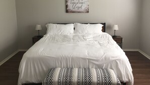A neatly made bed with white linens, two bedside lamps, and a decorative wall piece above the bed. - Perfect home for Baylor, Silos, and Business guests (Hewitt)