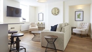 A modern living room with a sofa, armchairs, a coffee table, and a TV mounted on the wall. - 11 Redcliffe Parade (Bristol)