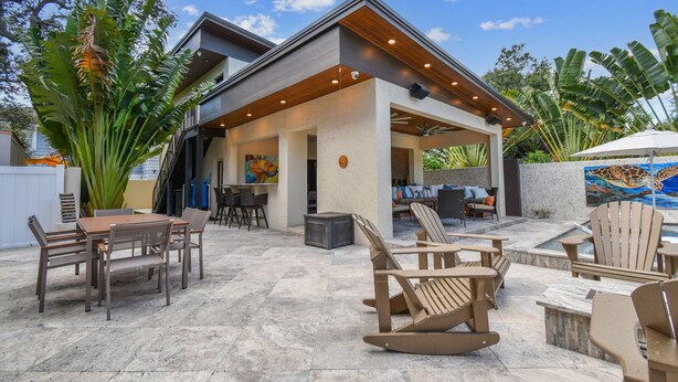 Een modern terras buiten met een eethoek, zitplaatsen en een overdekt gedeelte met kunstwerken.