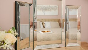 A bedroom with a bed, a bedside table, and a mirror. - The Stannary (Helston)