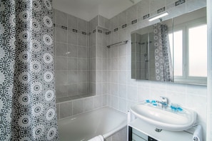 Ein Badezimmer mit Dusche, Badewanne, Waschbecken und Spiegel.