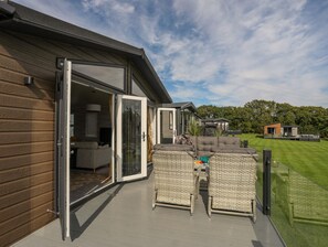 Ein modernes Haus mit einer Schiebetür zu einer Terrasse, die Korbmöbel und ein graues Sofa beinhaltet.