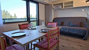 Un comedor con mesa de madera, sillas a rayas y un sofá al fondo.