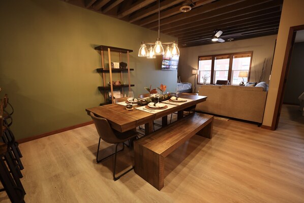 A dining area with a wooden table, benches, and a hanging light fixture. - Modern Rustic 2BR Condo in Downtown Minocqua—Walk to Shops, Dining & Lake (Minocqua)