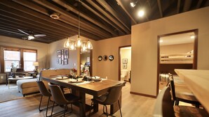 A dining area with a wooden table and chairs, a ceiling fan, and pendant lights. - Modern Rustic 2BR Condo in Downtown Minocqua—Walk to Shops, Dining & Lake (Minocqua)