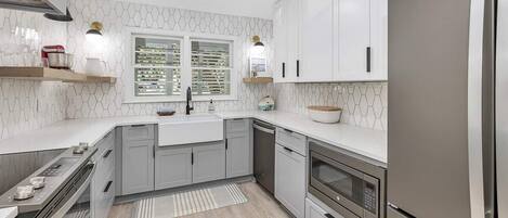 A modern kitchen with white cabinetry, a stainless steel refrigerator, and a built-in oven.