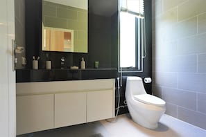 Ein modernes Badezimmer mit einem schwarz-weißen Waschtisch, einer Toilette und einem großen Spiegel.