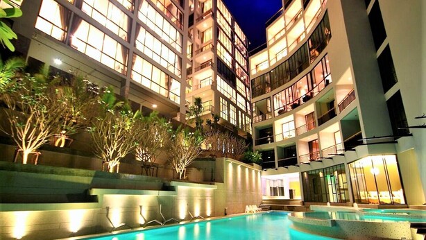 Un hotel de varios pisos con piscina, balcones y plantas de interior.