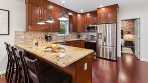 Una cocina moderna con armarios de madera, electrodomésticos de acero inoxidable y una encimera de granito.